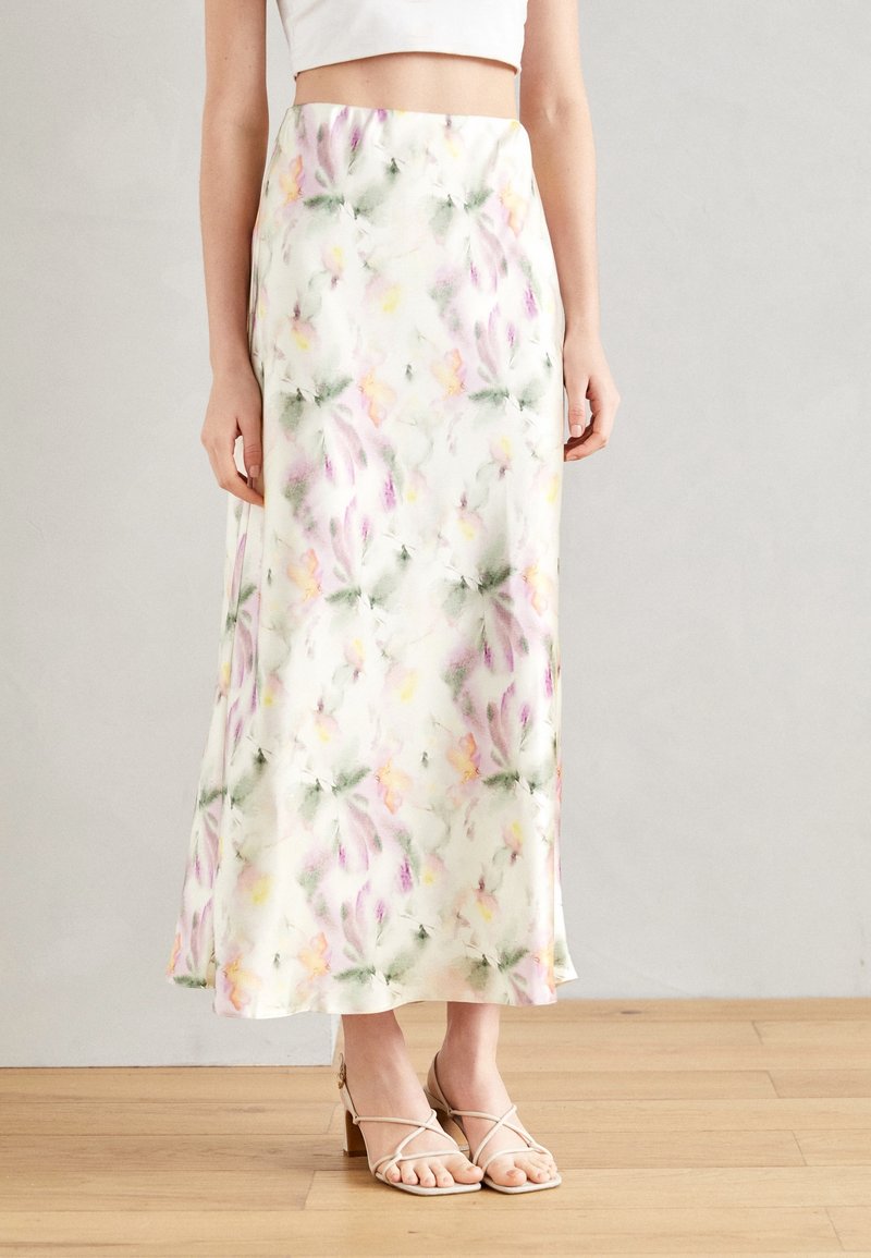 Korkeavyötäröinen satiinimekko pehmeällä pastellivärisellä kukkakuviolla, yhdistetty valkoiseen lyhytvartiseen puseroon ja beigekarvaiseen korkokenkään.