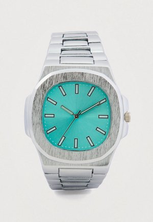 Montre-bracelet en métal argenté avec cadran turquoise, index noirs et trois aiguilles indiquant 10:10:36.