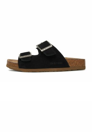 Sandalia tipo slide de ante negro con dos hebillas ajustables plateadas y una plantilla de corcho con suela de goma marrón.