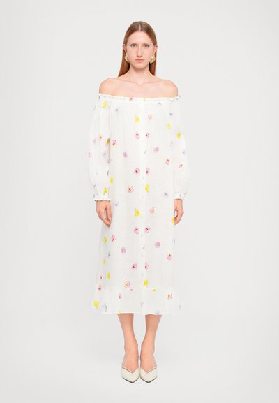 Vestido blanco sin mangas con estampados florales en púrpura, rosa y amarillo, con un frente de botones y un dobladillo con volantes.