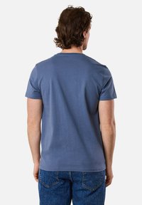 Short-sleeve blue cotton t-shirt with a crew neckline, featuring a plain design and a relaxed fit, paired with blue denim jeans.