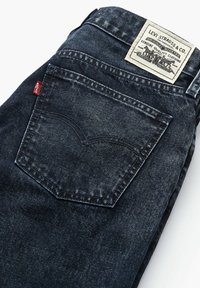 Jean en denim bleu foncé présentant un design délavé, des détails cousus et une étiquette Levi Strauss & Co. sur la ceinture arrière.