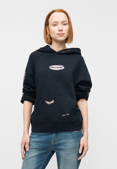 Μπλε σκούφο φούτερ με εμπρόσθια τσέπη, κεντητές λεπτομέρειες και λογότυπο. Διαθέτει κουκούλα με κορδόνι και ριμπ μανσέτες. Συνδυάζεται με ανοιχτόχρωμο μπλε τζιν παντελόνι.