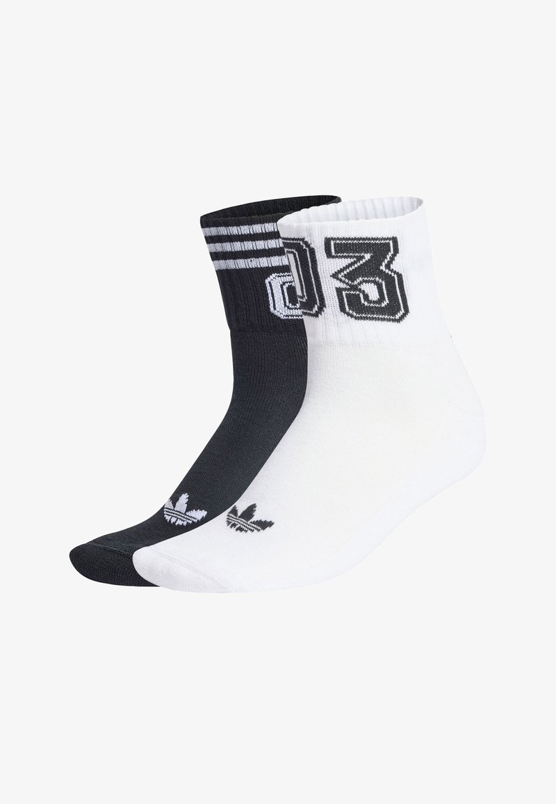 Calcetines tobilleros en blanco y negro hechos de mezcla de algodón. Presentan un gráfico audaz con el número 03 y tres rayas en el calcetín negro; logotipo pequeño en ambos.