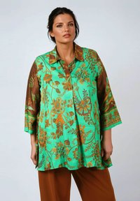 Floral patterned tunic in vibrant turquoise and brown. Features a classic collar, three-quarter sleeves, and a loose, flowing design.