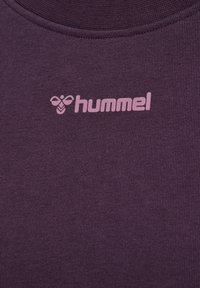 Paarse katoenen t-shirt met een ronde halslijn en een zachte textuur. Heeft een roze "hummel" logo gedrukt op de bovenste linkerzijde.