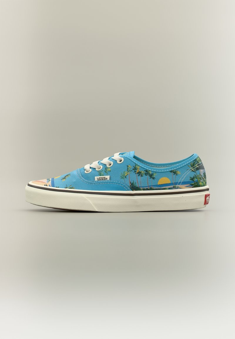 Baskets basses bleues Vans avec lacets blancs, imprimé palmier et coucher de soleil, semelle en caoutchouc blanche, et logo Vans sur le côté et le talon.