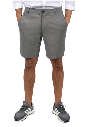 Gray shorts made of textured fabric, featuring a button closure, side pockets, and a tailored design, paired with gray athletic shoes.