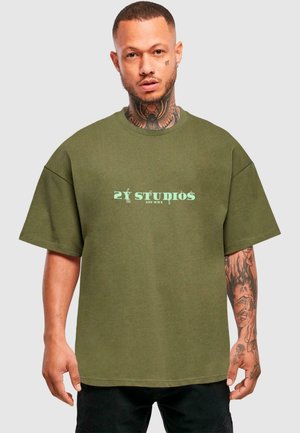 Olijfgroene oversized t-shirt met korte mouwen, met een muntgroen logo in het midden. Katoenen stof met een zachte textuur.
