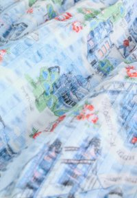 Světlá modrá látka s květinovým a architektonickým vzorem ve stylu akvarelu, s jemnou texturou a mírnými barevnými variacemi.