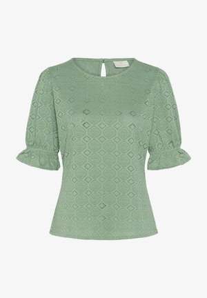 Blouse verte à manches courtes avec motif en dentelle de losanges et cercles, encolure ronde, fermeture au dos par bouton à fente, et poignets de manches à volants.