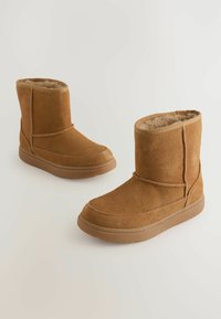 Rudi zomšiniai batai iki kulkšnies, su minkštu kailiniu pamušalu. Apvalus pirštas, siuvinėti detalės ir guminis padas, užtikrinantis sukibimą. Minimalistinis dizainas.