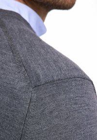 Maglione grigio lavorato a maglia con una finitura testurizzata, caratterizzato da un collo girocollo e cuciture visibili sulle spalle e sulle cuciture.