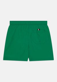 Pantaloni da bagno verdi con vita elasticizzata. Presenta una singola tasca posteriore con un'etichetta multicolore. Tessuto liscio e design semplice.