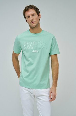 Camiseta de manga corta verde menta con "SALSA JEANS" impreso en texto blanco. Combinada con pantalones blancos, con un diseño simple y textura suave.