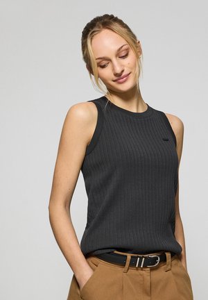 Donkergrijze geribbelde tanktop met een ronde halslijn en mouwloos ontwerp. In combinatie met hoogsluitende beige broek en een zwarte riem.