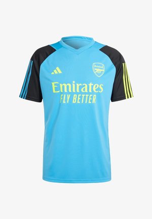 Maillot de football Arsenal bleu clair avec manches noires, logo Adidas jaune, écusson de l'équipe et texte du sponsor Emirates Fly Better.