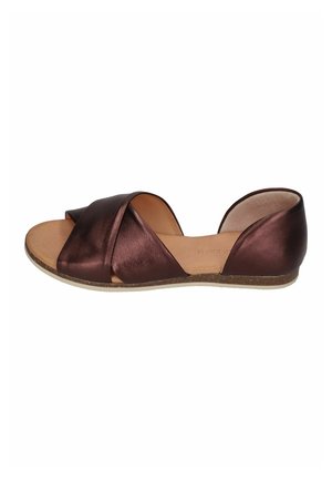 Brown leather flat sandal with crossed straps over toes and closed heel on light brown sole against white background.