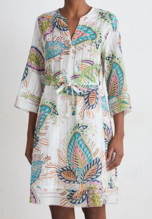 Robe blanche mi-longue aux genoux avec motifs abstraits colorés de feuilles, manches 3/4, col en V et ceinture à nouer à la taille.