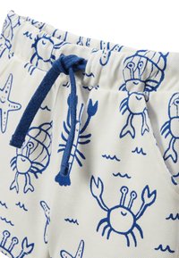 Shorts blancs avec un imprimé de crabes bleus, dotés d'un cordon de serrage bleu et d'une taille élastique. Le matériau semble texturé, léger et décontracté.