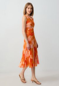 Fuchsia orange Kleid mit Blumenmuster, das ein figurnahes Oberteil und einen plissierten Rock aufweist, ergänzt durch eine weiche Textur und ärmelloses Design.