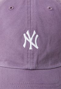Purple cotton baseball cap with a curved brim, featuring a white embroidered logo on the front, and visible stitching details.