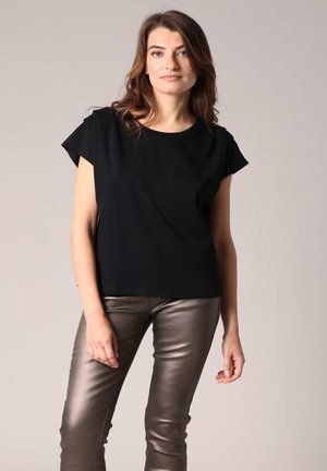 Haut noir à manches courtes avec une coupe décontractée, associé à un pantalon slim en bronze métallique brillant. Design simple et tissu léger.