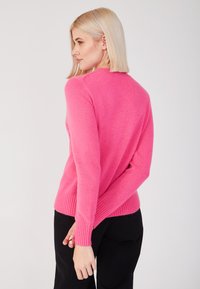 Suéter de punto rosa con mangas largas, puños y dobladillo acanalados, que presenta una textura suave y un escote redondo, visto desde la parte de atrás.