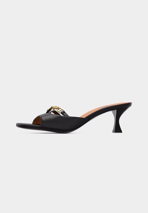 Black open-toe mule with low kitten heel and gold chain detail on the upper, shown in side profile on a white background.