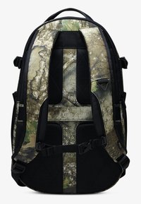 Batoh má maskáčový vzor v odtieňoch zelenej a hnedej farby, čierne akcenty, polstrované popruhy a nastaviteľný hardvér.