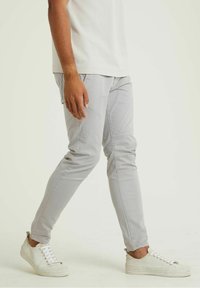 Lichtgrijze slim-fit broek van katoen. Voorzien van gestikte details en zijzakken. Gecombineerd met witte sneakers voor een casual uitstraling.