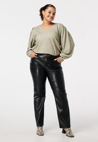 Lichtgroene v-hals pullover met pofmouwen, gecombineerd met hoge, zwarte neplederen broeken;accenten met slangenprint enkellaarsjes.