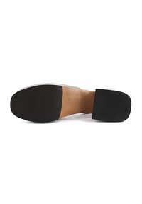 Semelle en caoutchouc noir avec une semelle intérieure beige lisse. Présente un talon carré avec une surface texturée et un design minimaliste.