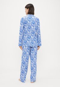 Kék és fehér paisley mintás pizsama szett, hosszú ujjú felsővel és laza fitnesz nadrággal, puha anyagból készült sima textúrával.