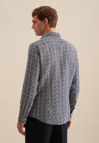 Camicia button-up blu navy con motivo floreale bianco, maniche lunghe e colletto. Il tessuto appare soffice con una finitura a trama.