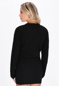 Czarna dzianinowa sukienka swetrowa z wzorem w warkocze, okrągłym dekoltem i długimi rękawami z bufkami, o teksturowanym wykończeniu.
