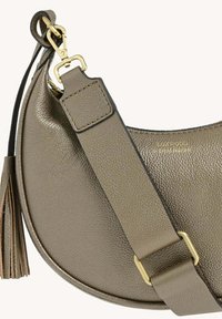 Sac à main rond en cuir métallique vert olive avec une finition texturée, une bandoulière amovible et un pompon décoratif. Accents en matériel doré.