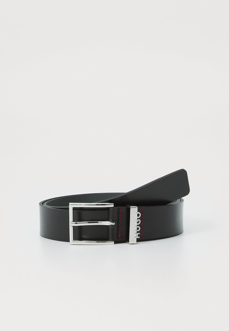 Ceinture en cuir noir avec une texture lisse, boucle en métal argenté et surpiqûres rouges. Largeur moyenne, adaptée à des tenues décontractées à formelles.