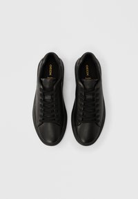 Ζευγάρι μαύρα δερμάτινα αθλητικά παπούτσια Geox με μαύρα κορδόνια, φωτογραφημένα από πάνω σε λευκό φόντο.