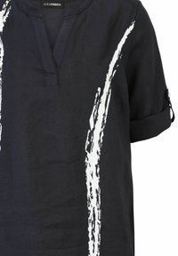 Zwarte linnen blouse met een V-hals en opgerolde mouwen, voorzien van een wit abstract penseelstrekenpatroon aan de voorkant. Zachte textuur.