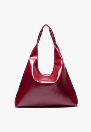 Rote glänzende Lederhandtasche mit dreieckiger Form, breiter Öffnung oben und einem geschwungenen Griff. Glatte Textur mit minimalen Nähdetails.