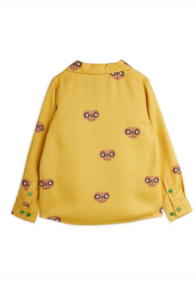 Κίτρινο πουκάμισο μακρυμάνικο με κουμπιά, που διαθέτει επαναλαμβανόμενο μοτίβο με καρτούν. Λεπτομέρειες περιλαμβάνουν πράσινα κουμπιά στους καρπούς και κλασικό γιακά.