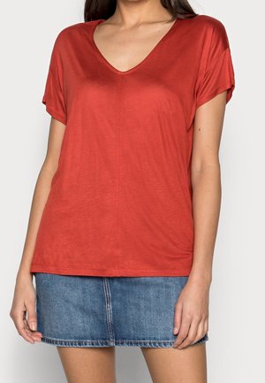 Czerwona, lekka, krótko rękawowa koszulka z dekoltem w serek, wykonana z gładkiego materiału, zestawiona z dżinsową mini spódniczką z centralnym szwem i przeszytym dołem.