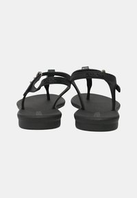 Sandali neri con infradito, suole piatte, fasce sottili e una fibbia posteriore. Il materiale appare liscio con un design minimalista e un dettaglio del logo sulle fasce.