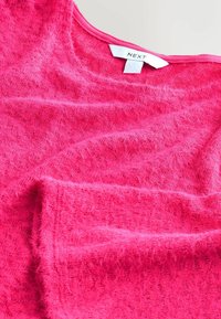 Różowy, teksturowany sweter z miękkiego materiału, z okrągłym dekoltem i metką z napisem "NEXT" wewnątrz.