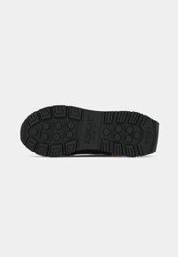 Semelle de chaussure noire avec des motifs de crantage prononcés, des grips circulaires et l'inscription "REPLAY SINCE 1981" en relief au centre.