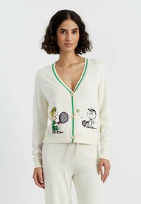 Romige cardigan met een diepe V-hals, groene accenten en houten knopen, versierd met gebreide afbeeldingen van cartoonpersonages die tennis spelen.