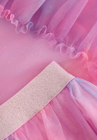 Tessuto di tulle rosa con bordi arricciati e una cintura glitterata rosa; texture morbida con elementi stratificati e traslucidi.
