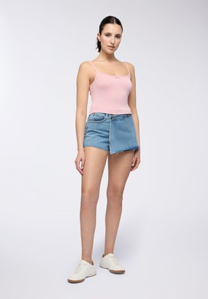 Top in maglina rosa a coste con spalline sottili, abbinato a una mini gonna di jeans chiari con orlo sfilacciato. Scarpe da ginnastica bianche completano l'outfit.