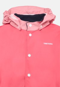 Wasserfeste rosa Regenjacke mit hohem Kragen, kontrastierendem marineblauem Futter, Druckknöpfen und TRETORN-Logo auf der Vorderseite.